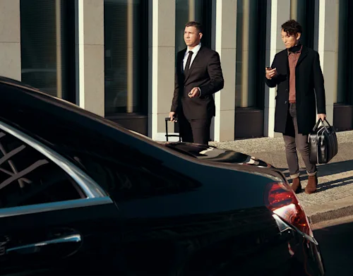Two business travelers walking to their waiting car