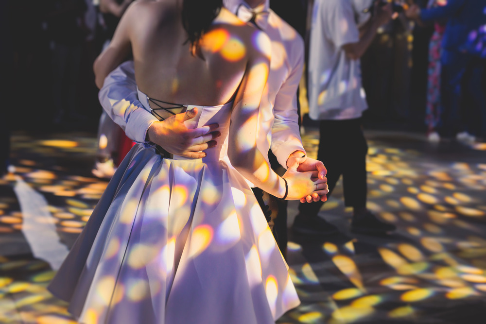 Couple dancing at prom under colorful lights